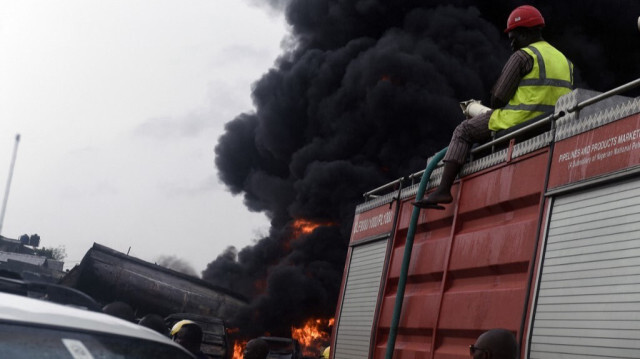 Un pompier est assis sur un camion alors que les gens regardent la fumée de l'incendie d'un oléoduc à Lagos, le 4 juillet 2019.