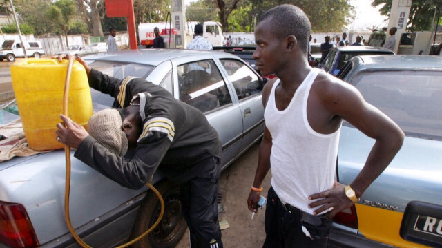 Un homme vend de l'essence sur le marché noir à un client dans un parking de station-service à Conakry au Guinée.