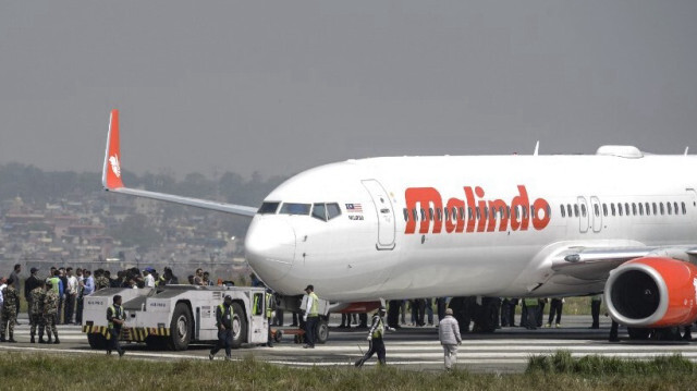 Des travailleurs népalais remettent en place un avion de ligne malaisien sur la piste à l'aéroport international de Katmandou le 19 avril 2018, après qu'il a dérapé hors de la piste suite à un décollage avorté.