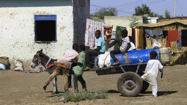 Des enfants déplacés de l'état de Jazira au Soudan transportent de l'eau sur une charrette tirée par un âne dans un abri temporaire à Gedaref, dans l'est du pays, le 28 décembre 2023.