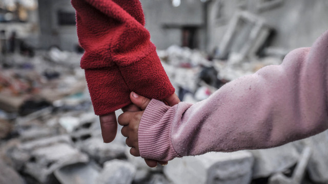 Des personnes se tiennent la main alors qu'elles inspectent les dégâts sur les bâtiments détruits par les bombardements israéliens à Rafah, dans le sud de la bande de Gaza, le 29 décembre 2023.