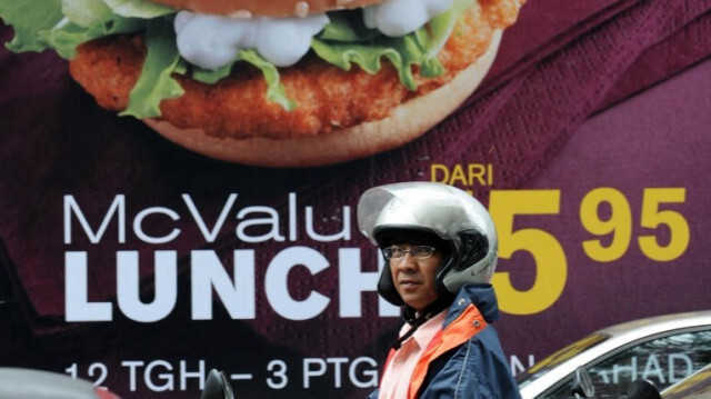 Un motocycliste attend dans la circulation devant un panneau publicitaire de la chaîne de restauration rapide américaine McDonald's, dans le centre-ville de Kuala Lumpur. (archive)