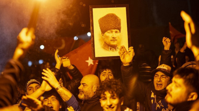 Des supporters turcs allument une fusée fumigène et tiennent un portrait de Mustafa Kemal Ataturk, fondateur de la Türkiye moderne, alors qu'ils attendent l'arrivée de l'équipe de football de Fenerbahce à Istanbul à l'aéroport Sabiha Gokcen d'Istanbul tôt le 30 décembre 2023.
