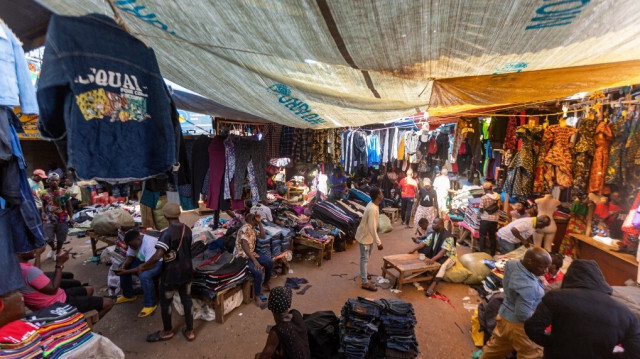 Les vendeurs offrant des vêtements d'occasion attendent les clients dans un marché à Kampala.