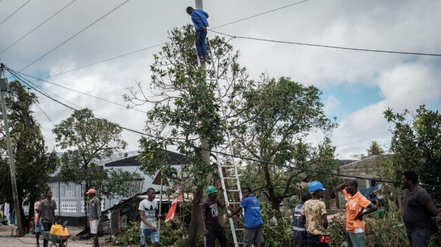 Un travailleur grimpe sur un poteau pour réinstaller des câbles à Beira, au Mozambique.