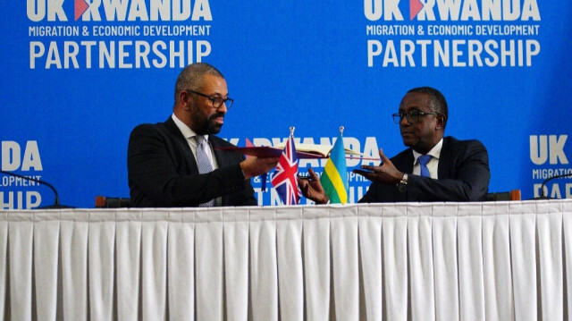 Le ministre britannique de l'Intérieur James Cleverly et le ministre rwandais des Affaires étrangères Vincent Biruta échangent des documents après la signature d'un nouveau traité, à Kigali le 5 décembre 2023.
