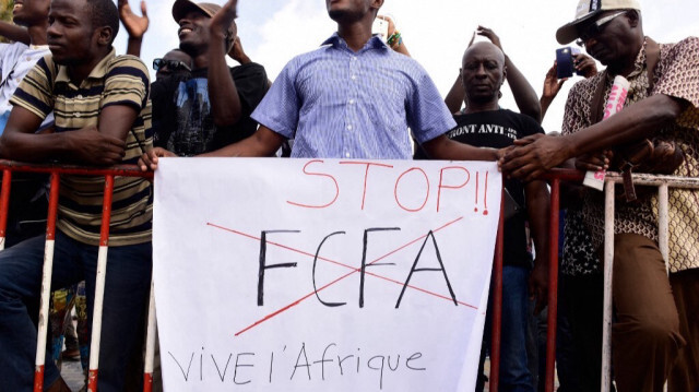 Un homme tient une pancarte sur laquelle on peut lire "Stop FCFA, vive l'Afrique".