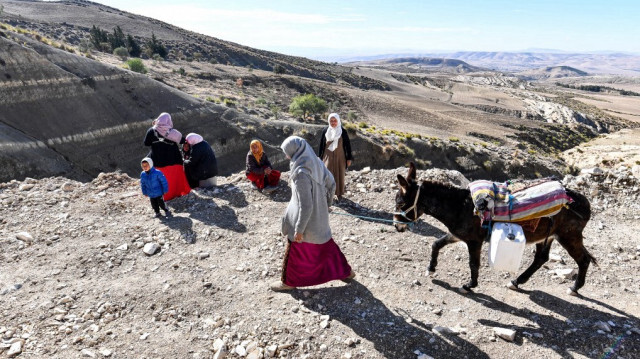 Une agricultrice tunisienne transporte l'eau qu'elle a remplie d'une rivière sur le dos d'un âne dans le village isolé d'Ouled Oma.