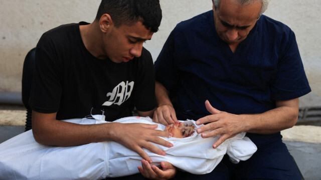Un jeune Palestinien et Talaat Barhom (D) avec le corps de son enfant Ahmed, âgé de 8 mois, lors des funérailles de sa femme et de quatre de ses enfants tués lors d'un bombardement de l'armée d'occupation israélienne, à Rafah, dans la bande de Gaza, le 6 novembre 2023.