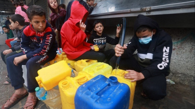 Des enfants palestiniens remplissent leurs jerrycans en plastique à partir d'une source d'eau dans le sud de la bande de Gaza, le 5 décembre 2023.