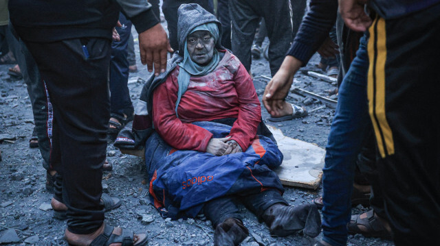 Une femme blessée par une frappe israélienne est assise au milieu des décombres à Rafah, dans le sud de la bande de Gaza, le 3 décembre 2023. Israël a procédé à des bombardements meurtriers dans la bande de Gaza le 3 décembre, alors que les appels internationaux se multiplient pour une meilleure protection des civils et le renouvellement d'une trêve expirée.