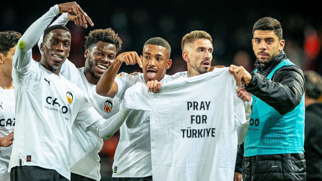 "Türkiye için dua edin" yazılı tişörtü kameralara gösteriler.