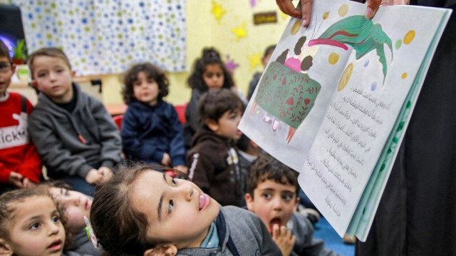 L'enseignante jordanienne Huda Abu al-Khair, lit des histoires à des enfants dans une salle de classe à Amman en Jordanie. Crédit photo:  KHALIL MAZRAAWI / AFP