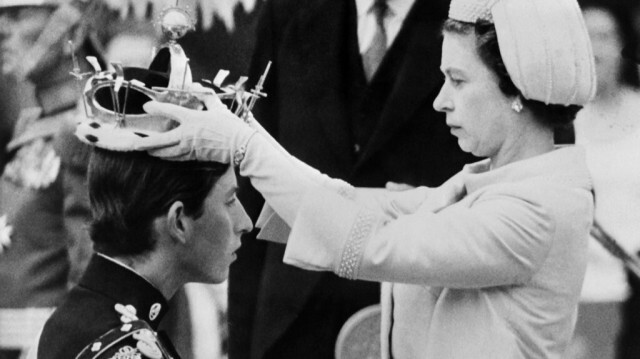 Sur cette photo prise le 1er juillet 1969, la reine Élisabeth II pose une couronne sur son fils, le prince Charles, lors de son investiture en tant que nouveau prince de Galles à Caernarfon. Crédit photo: CENTRAL PRESS / AFP