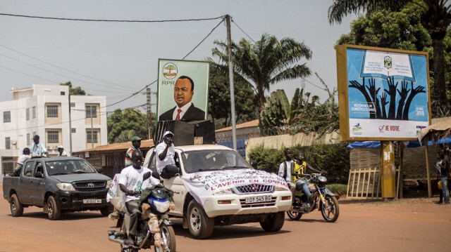 Des partisans qui passent devant l'affiche d'Alexandre-Ferdinand N'Guendet . Crédit Photo: MARCO LONGARI / AFP