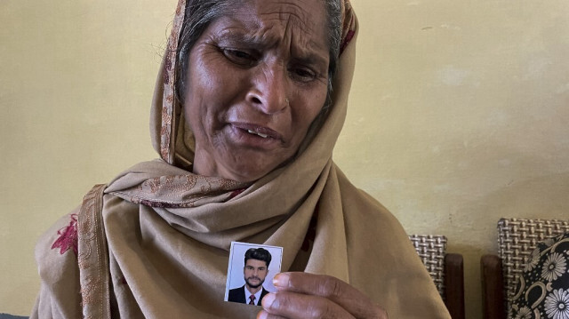 La mère d'un migrant porté disparu après le naufrage d'un chalutier surchargé au large des côtes grecques, tenant une photo de son fils, dans le village de Bandli, dans le Cachemire administré par le Pakistan. Crédit photo: SAJJAD QAYYUM / AFP