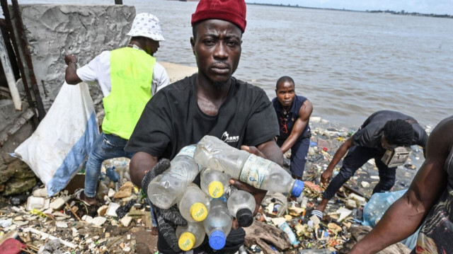 Des résidents ramassent des bouteilles et des sacs en plastique dans la lagune d'Ébrié à Abidjan. Crédit photo: ISSOUF SANOGO / AFP