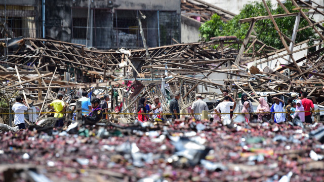 Les gens regardant les séquelles des maisons détruites le lendemain d'une explosion qui a détruit un entrepôt de feux d'artifice dans le district de Sungai Kolok, dans la province de Narathiwat, le 30 juillet 2023. Crédit Photo: Madaree THOLALA / AFP

