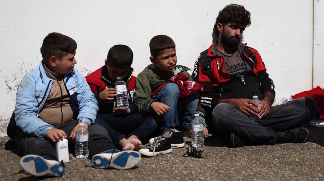 Des migrants en attente du bus pour être reconduit à Dungeness, en Angleterre, le 16 août 2023, après avoir été secourus en mer alors qu'ils traversaient la Manche depuis la France. Crédit photo: HENRY NICHOLLS / AFP
