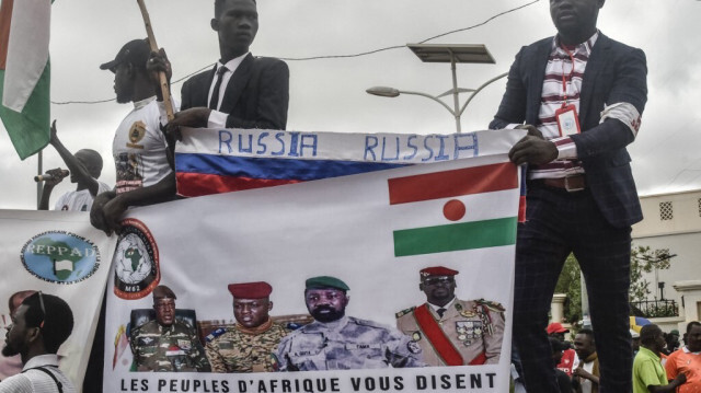 Les manifestants tiennent un drapeau russe et une bannière avec des images de (de gauche à droite) : le général Abdourahamane Tchiani, le nouvel homme fort du Niger, le chef de la junte du Burkina Faso, le capitaine Ibrahim Traore, le chef de la junte du Mali, Assimi Goita, et le chef de la junte de Guinée, le colonel Mamady Doumbouya. Crédit photo: AFP