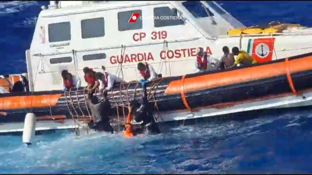 Les migrants tentant de grimper à bord du vaisseau ballotté par les vagues, lors du sauvetage en Italie. Crédit photo: ITALIAN COASTGUARD / GUARDIA COSTIERA / AFP
