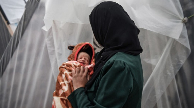 Une mère gazaouie, qui a été déplacée alors qu'elle était enceinte de 7 mois en raison des attaques israéliennes, s'est réfugiée dans une tente, tenant sa fille Sukkar dans ses bras à Gaza, le 23 décembre 2023.