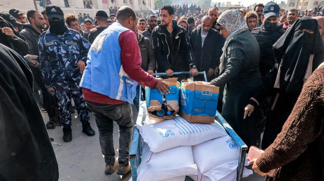 Des travailleurs de l'Office de secours et de travaux des Nations Unies pour les réfugiés de Palestine (UNRWA) distribuant des rations de farine et d'autres fournitures à des personnes dans un entrepôt de l'UNRWA à Rafah, dans le sud de la bande de Gaza, le 12 décembre 2023.