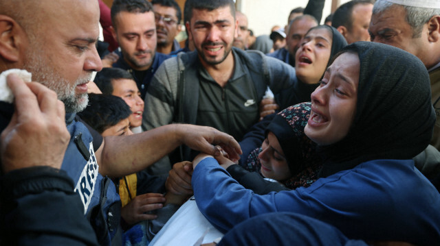 La veuve (à droite) de Hamza Wael Dahdouh, journaliste du réseau de télévision Al Jazeera, et son père, Wael Al-Dahdouh, chef du bureau d'Al Jazeera à Gaza (à gauche), se recueillant sur son corps lors de ses funérailles, après qu'il ait été tué lors d'une frappe aérienne israélienne, à Rafah, dans la bande de Gaza, le 7 janvier 2024.