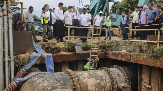 Les travailleurs remplacent les vannes d'eau de l'usine de traitement de l'eau de Sungai Dua, alors que le ministre en chef de Penang, Chow Kon Yeow (centre supérieur L), inspecte leurs progrès à Penang, en Malaisie, le 10 janvier 2024.