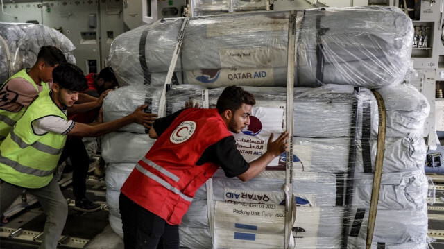 Un membre du Croissant-Rouge égyptien et d'autres travailleurs déchargent un envoi d'aide humanitaire destiné à la Bande de Gaza d'un avion de transport militaire qatari.