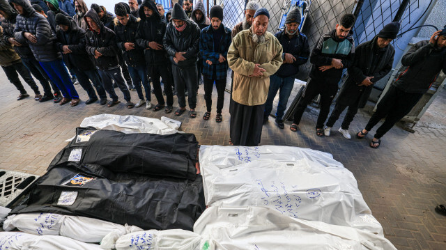 Des personnes priant devant les corps enveloppés de leurs proches tués lors de bombardements israéliens, le 13 janvier 2024, dans la cour de l'hôpital Al-Najjar à Rafah, dans le sud de la bande de Gaza.