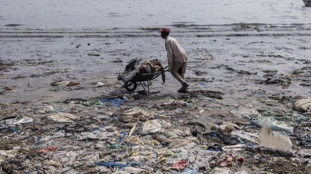 Sur la longue plage de la baie de Hann à Dakar, un homme seul, muni d'une pelle et d'une brouette, ramasse inlassablement des monceaux d'ordures.