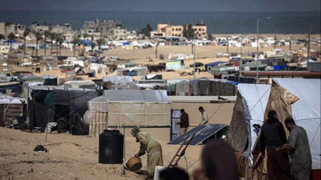 Des Palestiniens déplacés se rassemblent dans un camp de fortune à la frontière égyptienne, à l'ouest de Rafah, dans le sud de la Bande de Gaza, le 14 janvier 2024.