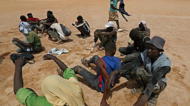 Des migrants africains, qui auraient été abandonnés par les autorités tunisiennes, se reposent à leur arrivée dans une zone inhabitée près d'Al-Assah, à la frontière entre la Libye et la Tunisie, le 30 juillet 2023. 