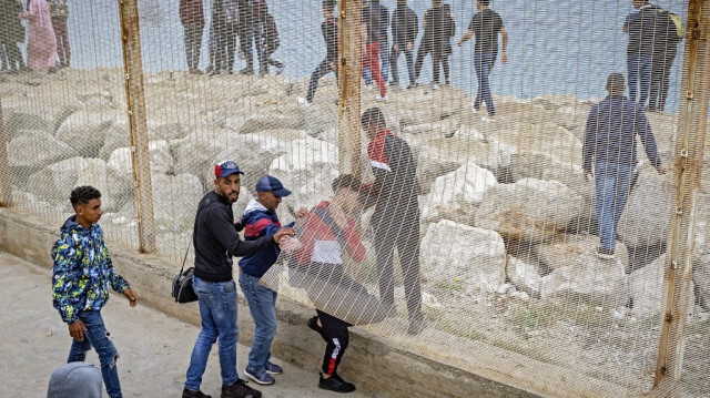 Les migrants se glissent à travers une clôture dans la ville de Fnideq, au nord, pour tenter de traverser la frontière entre le Maroc et l'enclave espagnole de Ceuta, en Afrique du Nord, le 18 mai 2021.