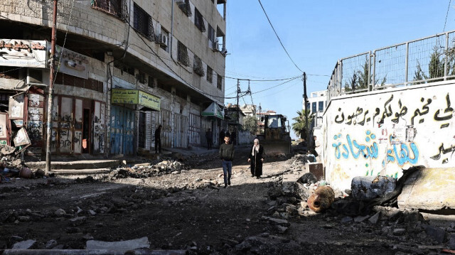 Des Palestiniens marchent au milieu des décombres dans une rue du camp de réfugiés de Tulkarm, où l'armée israélienne a mené des raids nocturnes, le 19 janvier 2024.