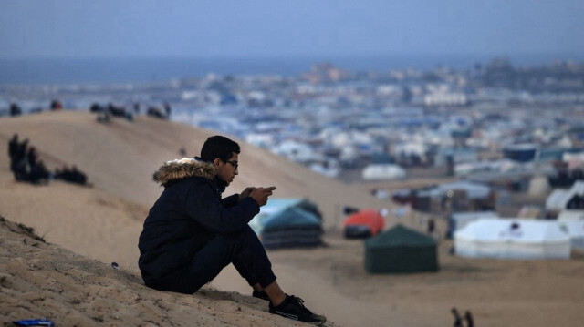 Un Palestinien déplacé utilisant une carte eSIM tente d'obtenir un signal pour contacter ses proches le 19 janvier 2024, sur une colline à Rafah, dans le sud de la bande de Gaza.