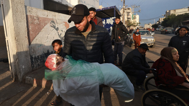 Un parent portant le corps enveloppé de Masa Shoman, qui a été tué lors d'un bombardement israélien, à l'extérieur de l'hôpital Najjar à Rafah, dans le sud de la bande de Gaza, le 17 janvier 2024.