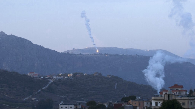 Des volutes de fumée s'élèvent d'une maison touchée par des frappes aériennes israéliennes, alors que des fusées éclairantes tombent sur le village libanais de Kfar Kila, près de la frontière avec Israël, le 19 janvier 2024.