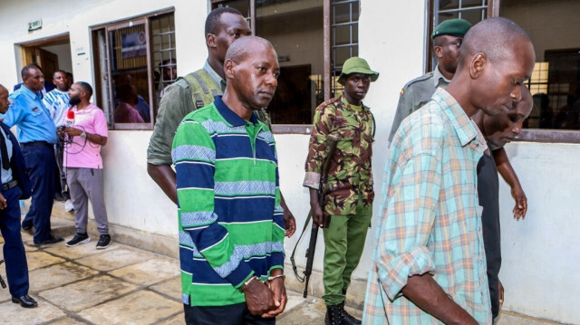 Le pasteur autoproclamé Paul Nthenge Mackenzie (C) est entouré d'officiers de la police kenyane et d'autres accusés lors de sa comparution au tribunal de Shanzu à Mombasa, le 18 janvier 2024.