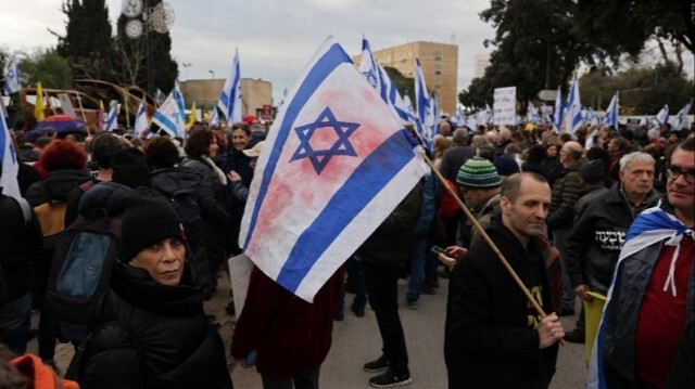 Des manifestants brandissent des pancartes et des drapeaux nationaux lors d'un rassemblement demandant la libération des Israéliens devant le Parlement israélien à Jérusalem, le 15 janvier 2024.