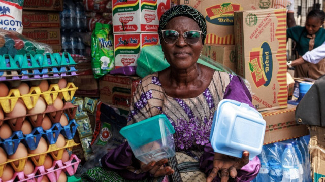 Mme Bakare Kehinde, une ancienne directrice, détient divers types d'assiettes en plastique dans son magasin à Lagos, le 23 janvier 2024. 