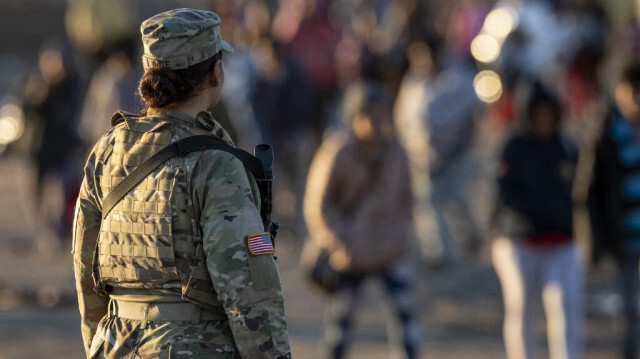 Un soldat de la Garde nationale du Texas observe des milliers d'immigrants qui se dirigent vers un centre de transit de la patrouille frontalière américaine, le 19 décembre 2023 à Eagle Pass, au Texas.