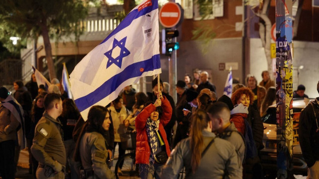 Une femme brandit le drapeau national alors que les forces de sécurité israéliennes dispersent les manifestants en marge d'un rassemblement appelant à la démission du gouvernement et à des élections anticipées, à Tel Aviv, le 27 janvier 2024.