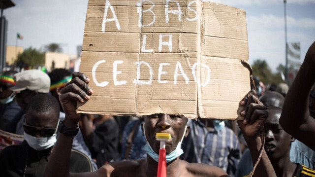 Un manifestant tient une pancarte où il est écrit "À bas la CEDEAO", lors d'une manifestation de masse pour protester contre les sanctions imposées au Mali et à la junte par la Communauté économique des États de l'Afrique de l'Ouest (CEDEAO), à Bamako le 14 janvier 2022. 