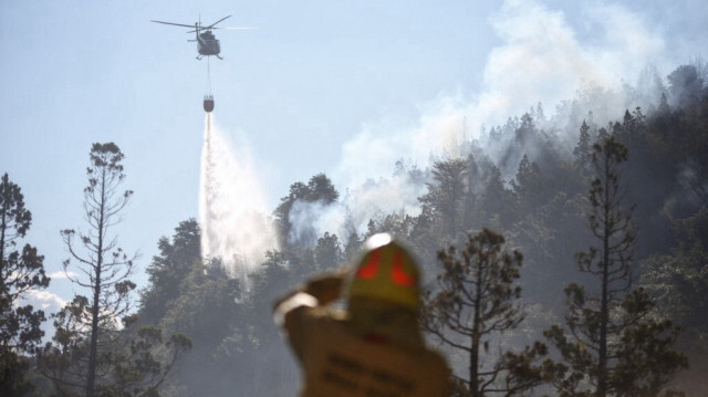 Un hélicoptère larguant de l'eau pour éteindre le feu de forêt dans le parc national de Los Alerces, dans la province de Chubut, en Argentine, le 26 janvier 2024.