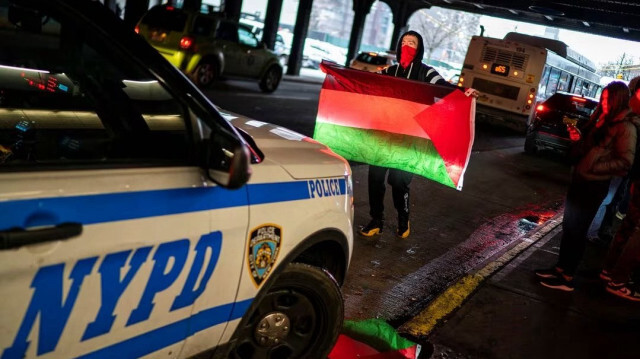 Пропалестинский демонстрант пытается остановить автомобиль полиции Нью-Йорка, в то время как другие принимают участие в акции протеста, у вокзала Ямайка, США, 27 января 2024 года.