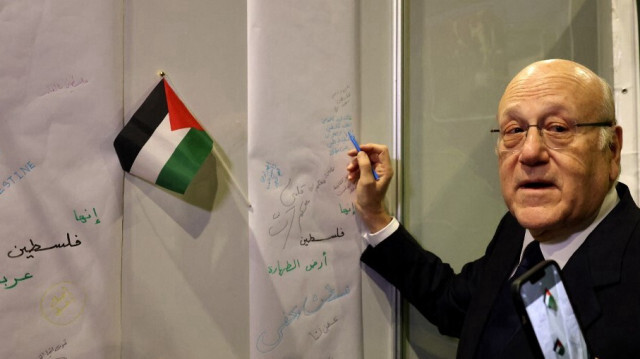 Le Premier ministre du Liban, Najib Mikati, rédige un paragraphe en soutien aux Palestiniens lors de sa visite à la 65e Foire internationale du livre de Beyrouth, le 23 novembre 2023.