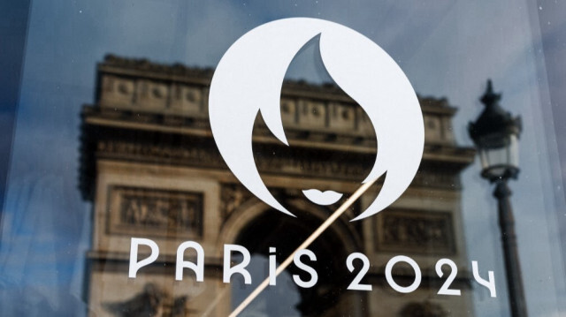 L'Arc de Triomphe se reflète dans la vitrine d'un magasin officiel pour les Jeux Olympiques et Paralympiques d'été de Paris 2024.
