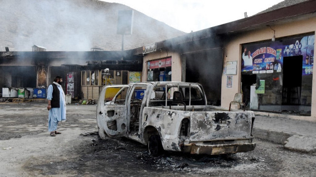 Un homme regarde des magasins carbonisés et un véhicule incendié par le groupe séparatiste armé de l'Armée de libération du Baloutchistan (BLA) dans le district central de Bolan dans la province du Baloutchistan le 30 janvier 2024.